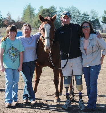 Members of the Cornerstone Therapeutic Riding Center and a recent participant pose for a photo with one of the therapy horses.
