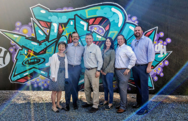 Leadership team members standing in front of a graffiti art mural.