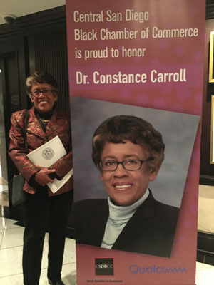 Dr. Constance Carroll standing in front of a poster honoring her