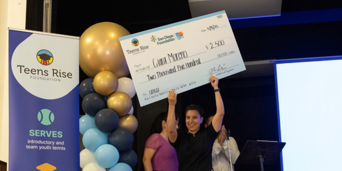 A woman holding a Teens Rise giant award check