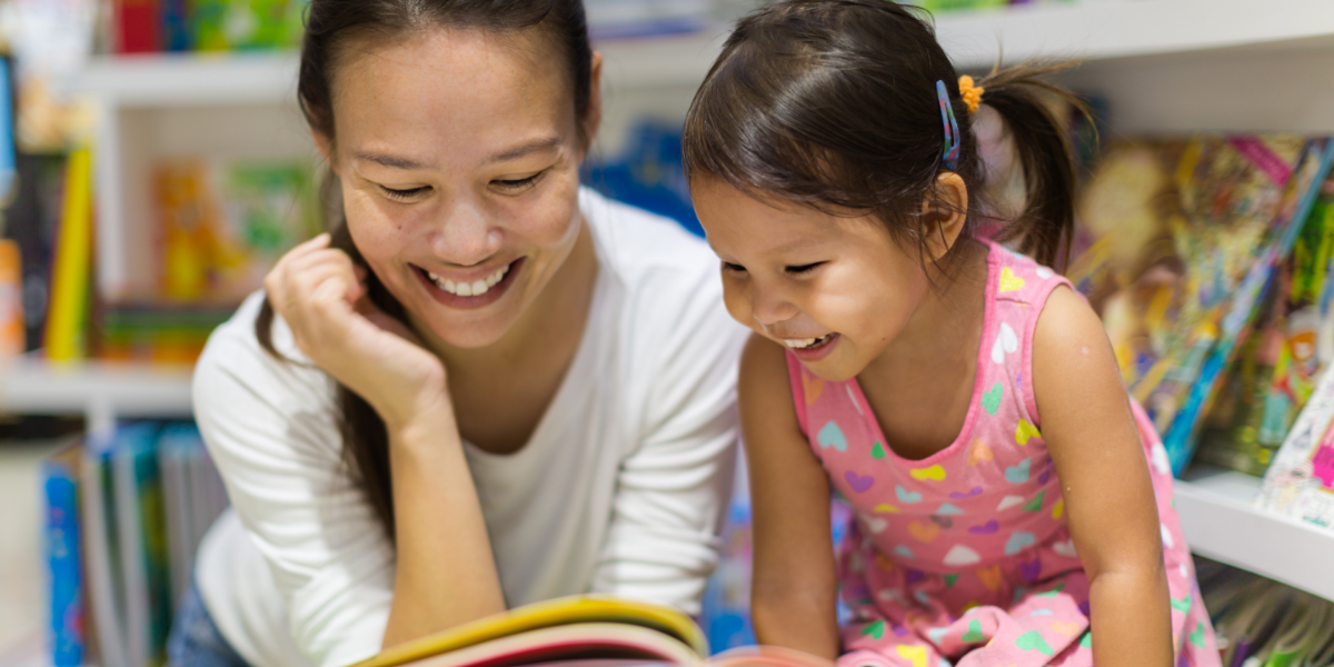 Adult and young girl reading a book together