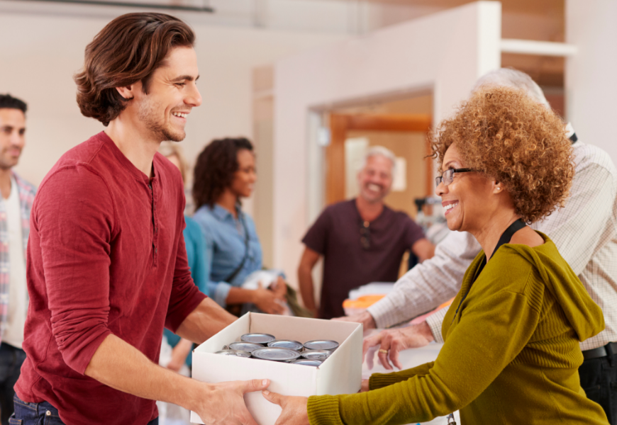 Food bank volunteer giving canned goods to another person