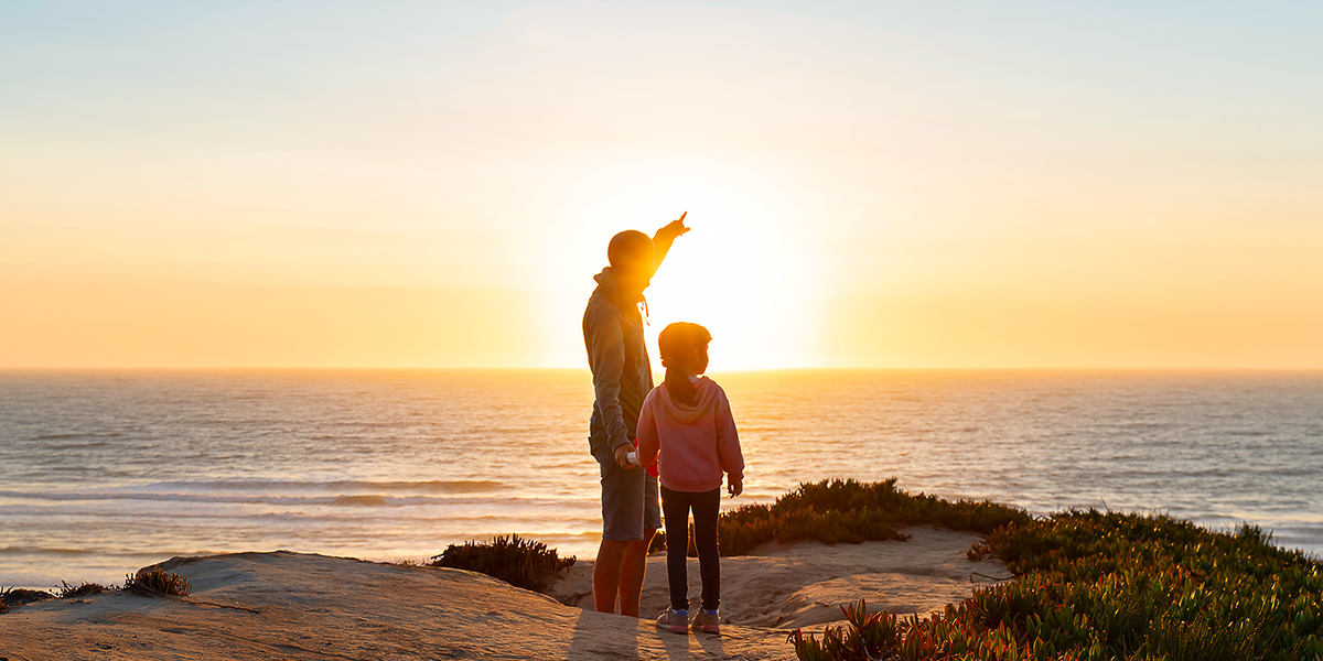 Adult and child looking at sunset