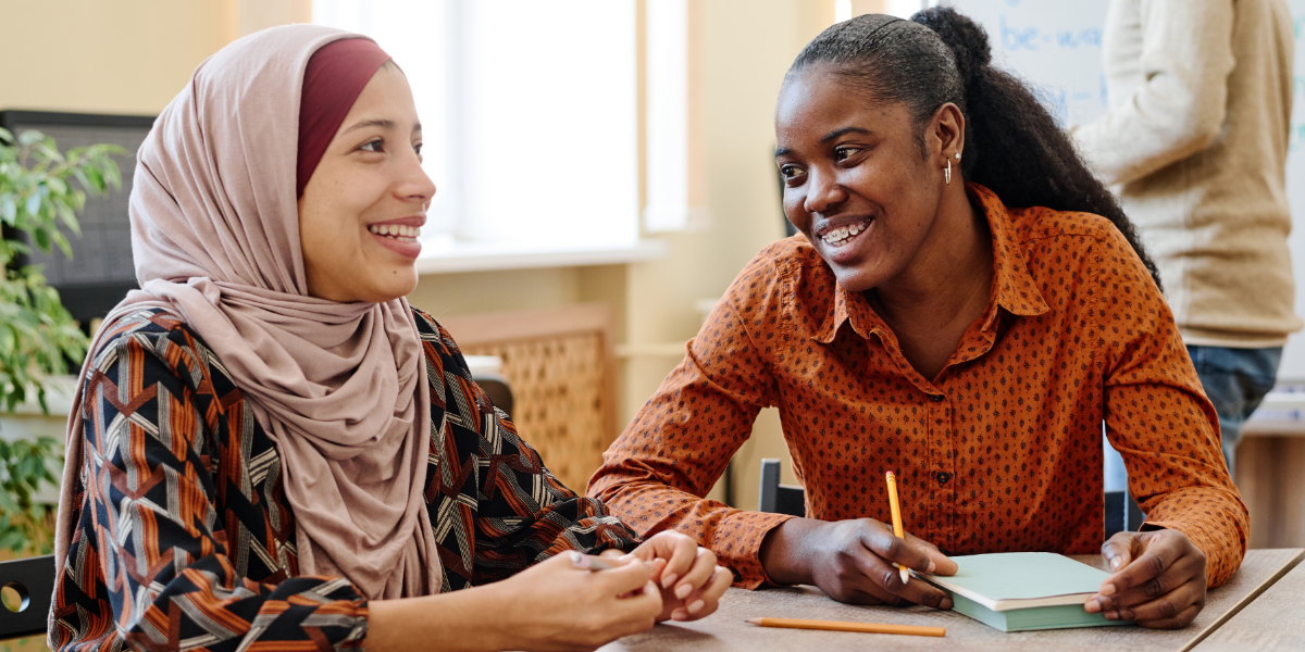Two women at a desk smiling and conversing