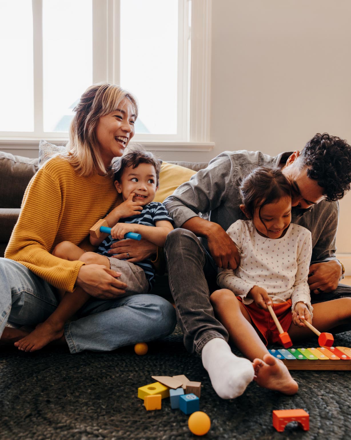 Family on the floor playing in living room with young kids