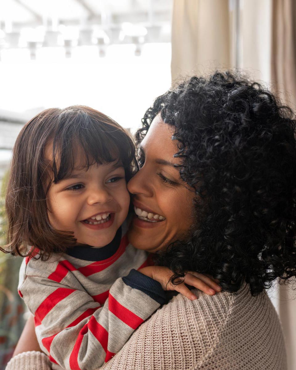Mom and daughter hugging and smiling with their faces touching